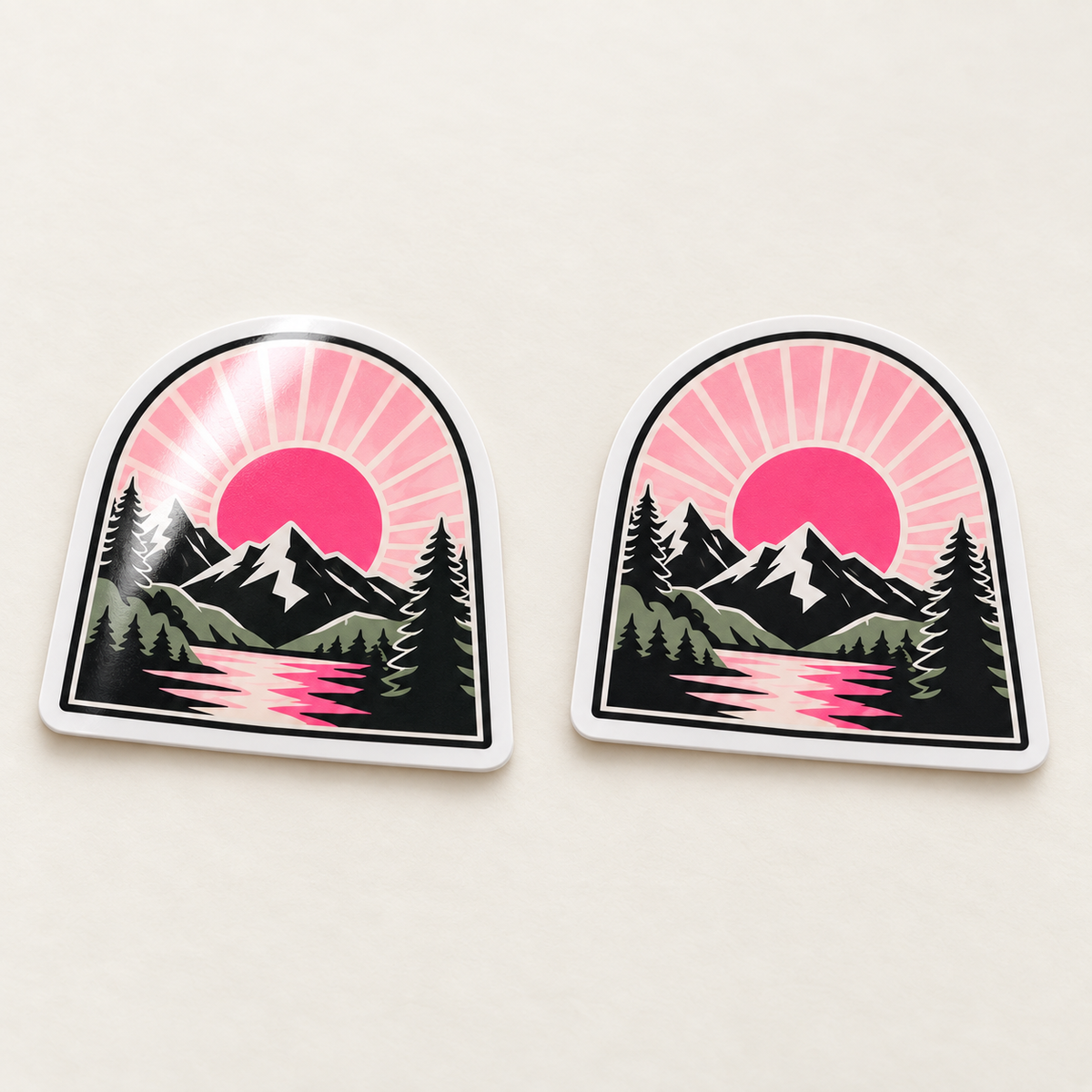 AI-generated illustration: Two matching pink mountain landscape stickers side by side, with a soft reflection on the glossy left sticker and a diffuse matte finish on the right.